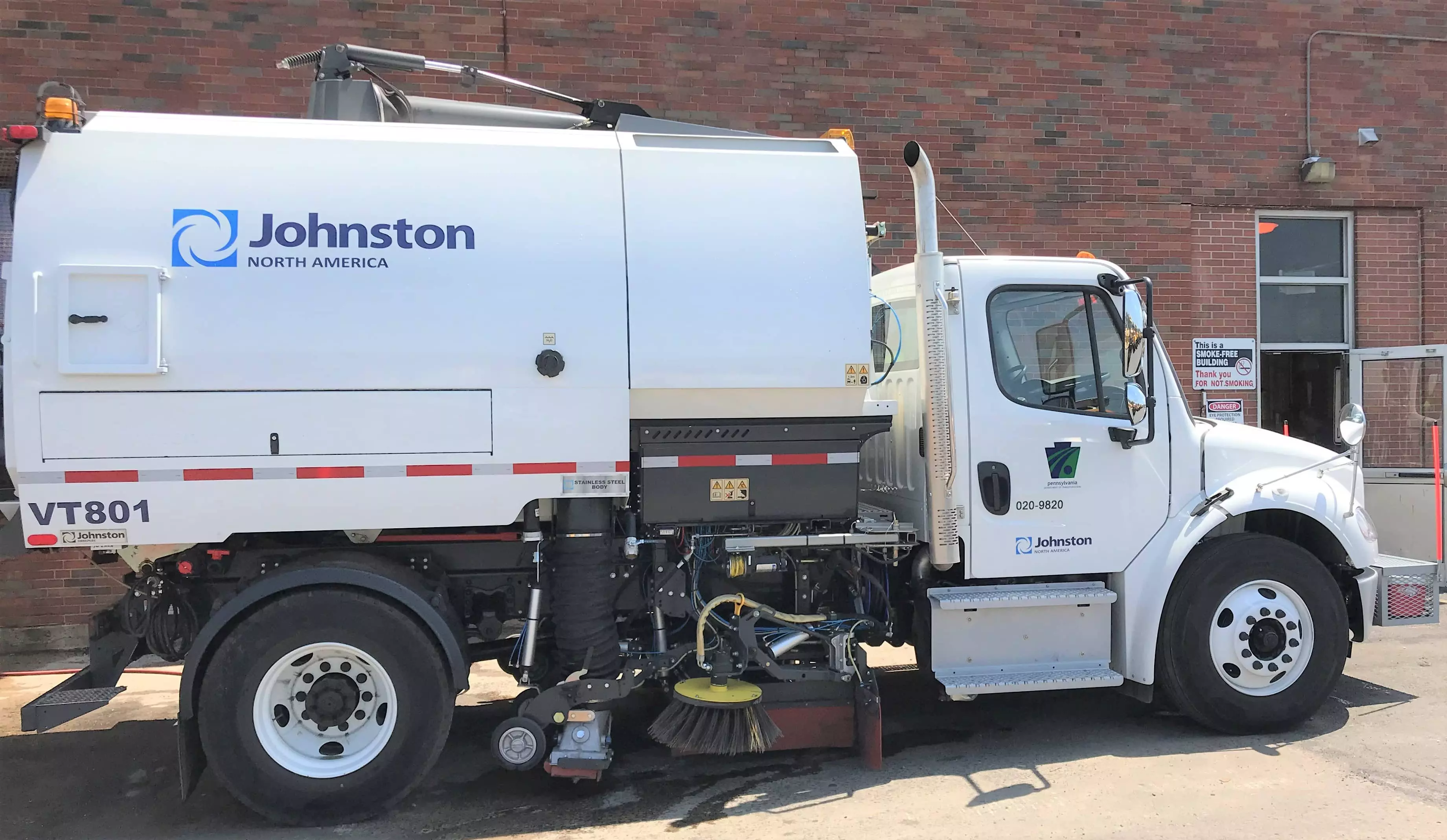 PennDOT's sweeper truck is parked outside a PennDOT facility, displaying brush and vacuum features on the passenger side.
